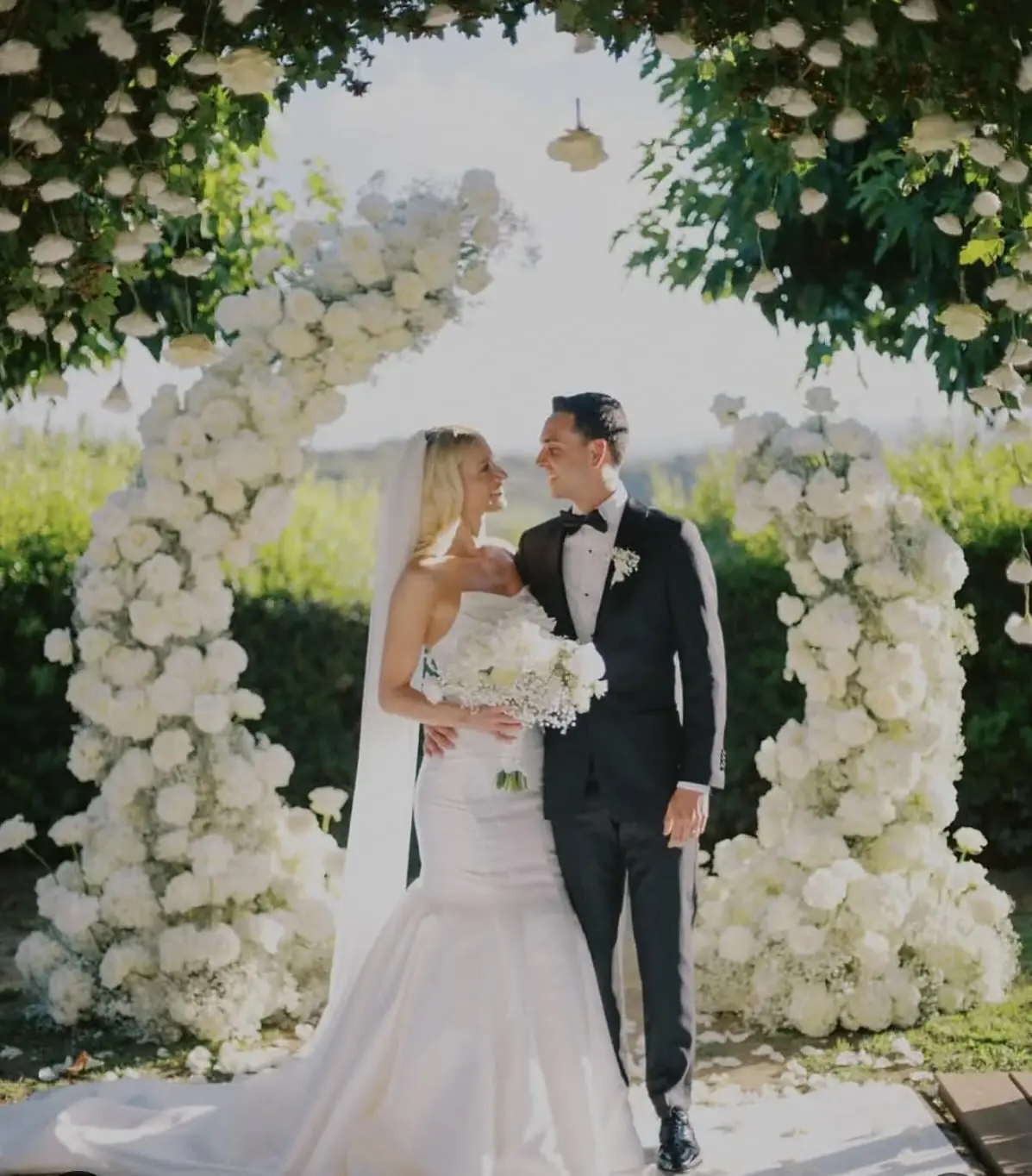 Efffetti® | Wedding Planner in Italy & Tuscany Bride and groom under a white flower arch in a garden
