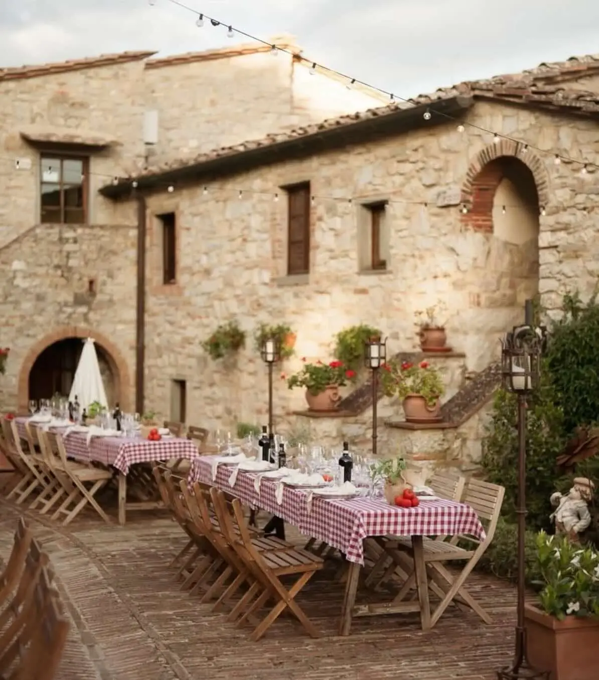 Efffetti® | Wedding Planner in Italy & Tuscany Long dinner tables with gingham tablecloths in a stone farmhouse courtyard in Tuscany